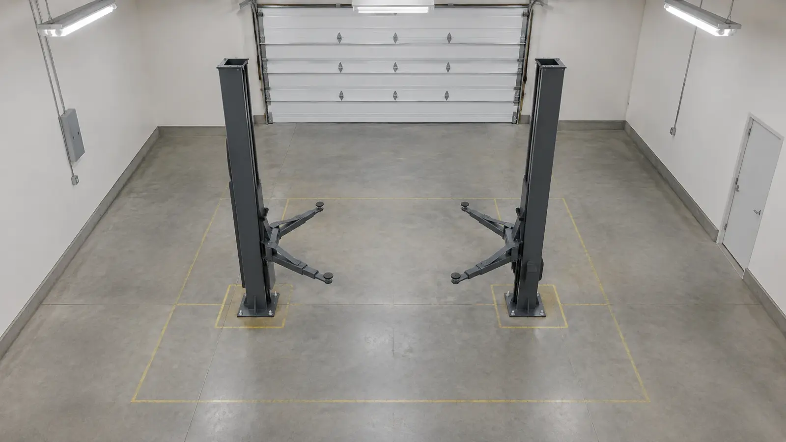 Overhead view of an empty garage bay with floor clearance marked around a car lift.